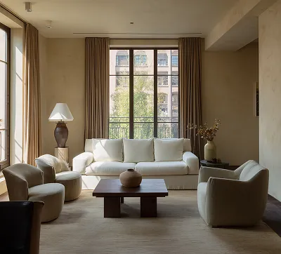 Un salon moderne avec deux grandes fenêtres, un design minimaliste, des sols et des meubles en bois chaleureux, alliance réussie du confort et de l’élégance architecturale.