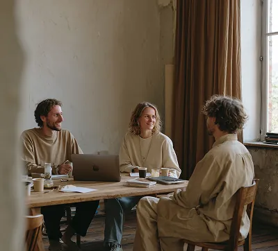 Trois architectes qui échangent sur des plans, image de la collaboration et d’une planification de projet experte.