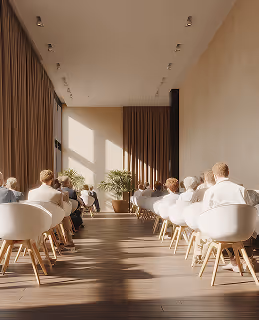 Une vaste pièce sous haut plafond, avec de nombreuses chaises et tables occupées, un aménagement fonctionnel qui favorise les échanges et le confort.